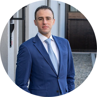 Man in blue blazer and light blue tie, circular professional portrait
