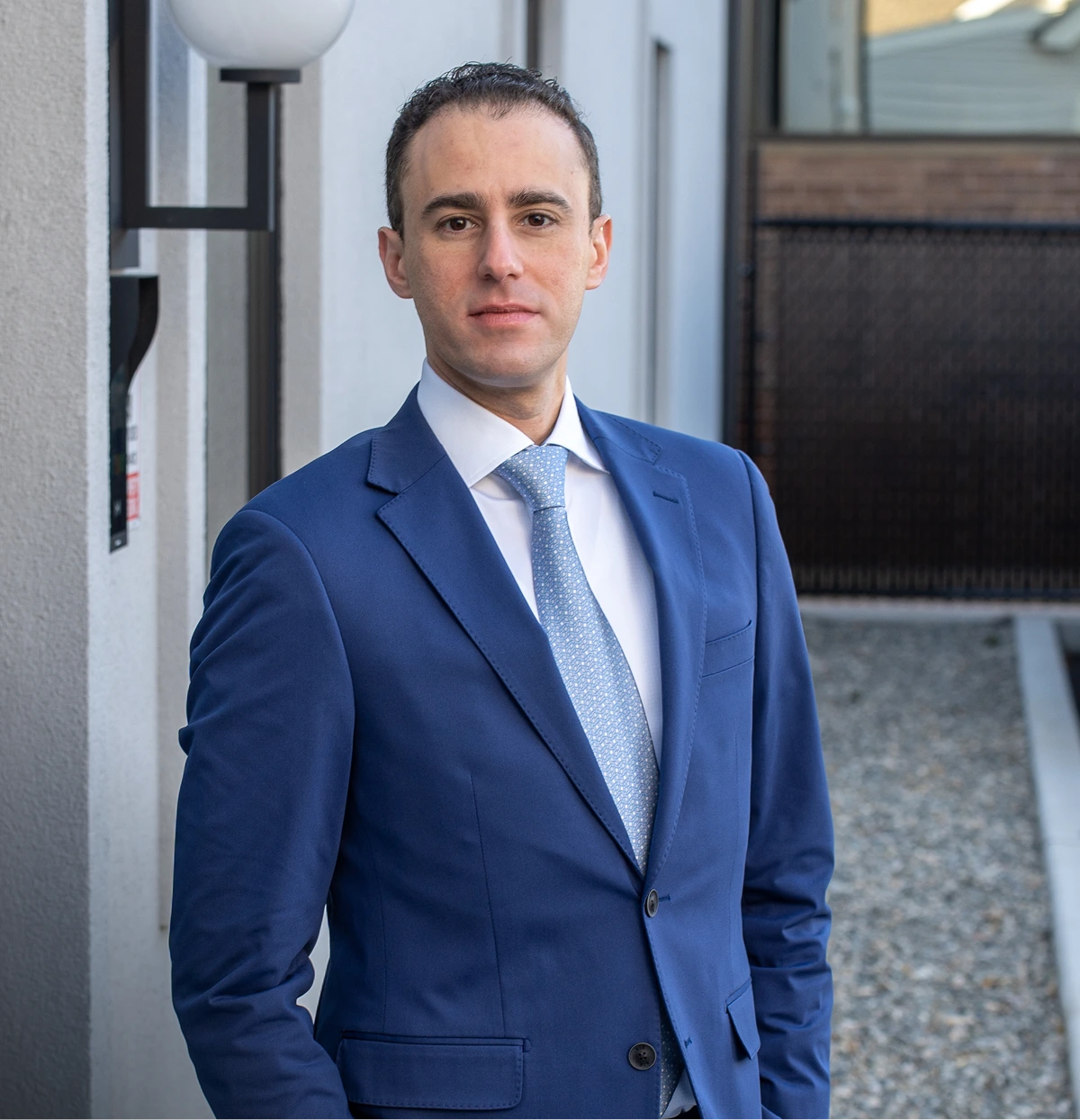 Dr. Daniel Bienstock in blue suit and tie, standing in modern office entrance