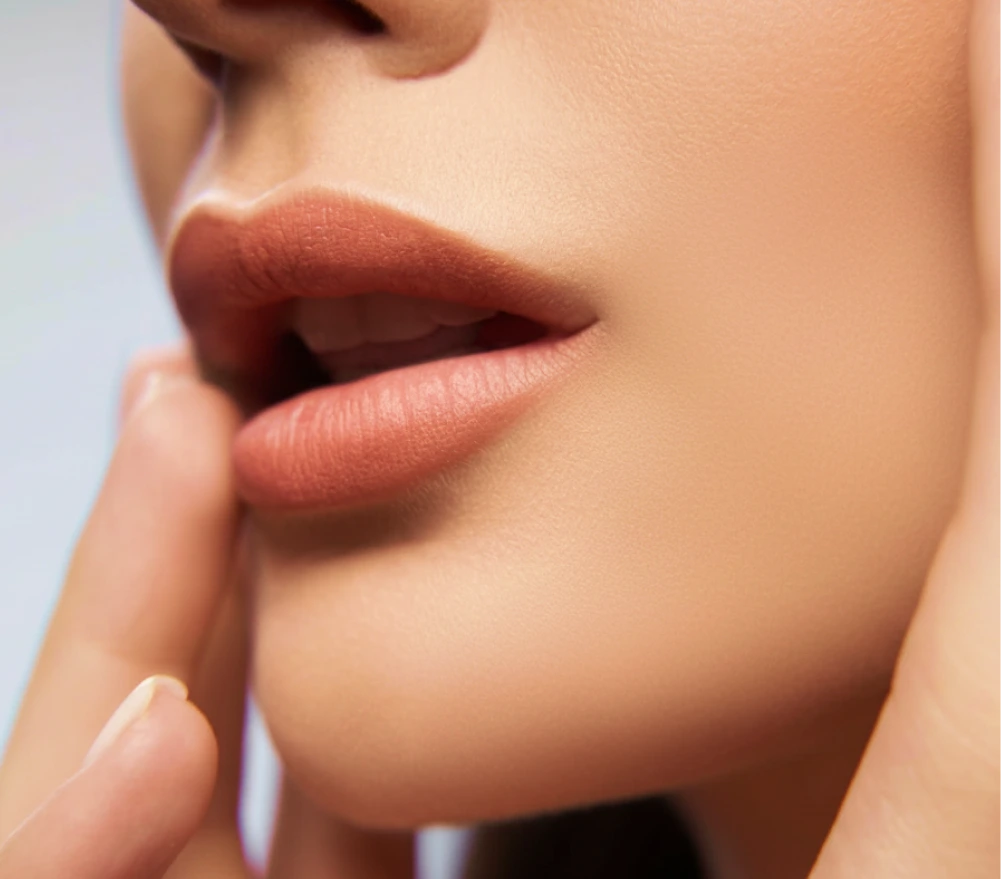 Close-up of woman's fuller lips with finger touching her cheek