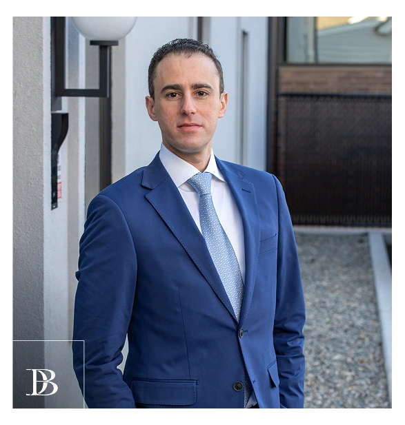Dr. Daniel Bienstock in blue suit and tie standing in modern office hallway