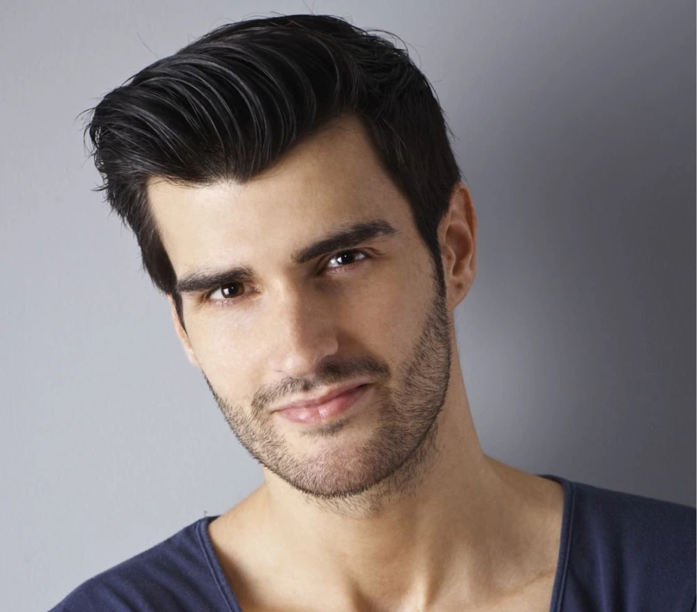 Man with full dark hair styled back, displaying hair restoration results