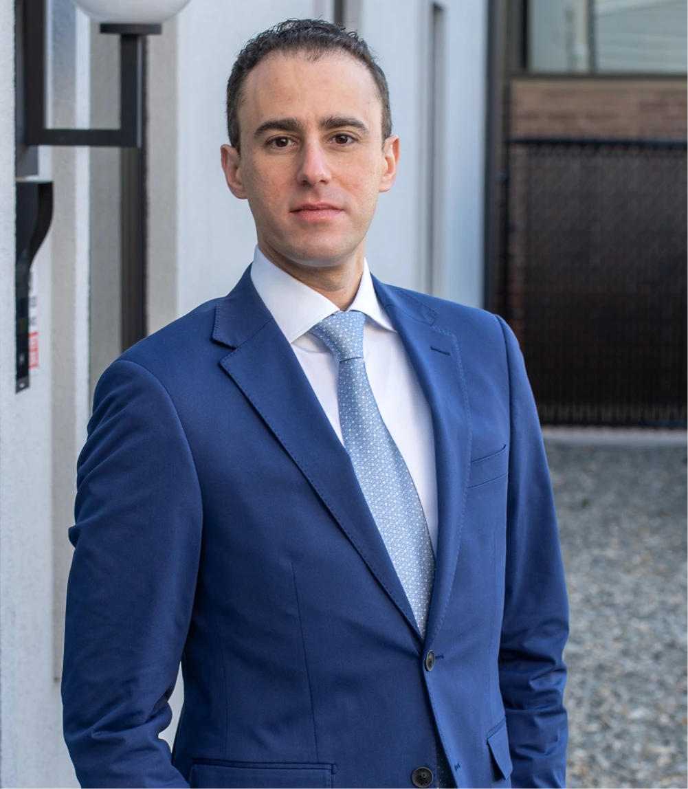 Dr. Daniel Bienstock in blue suit and tie standing in modern clinic hallway