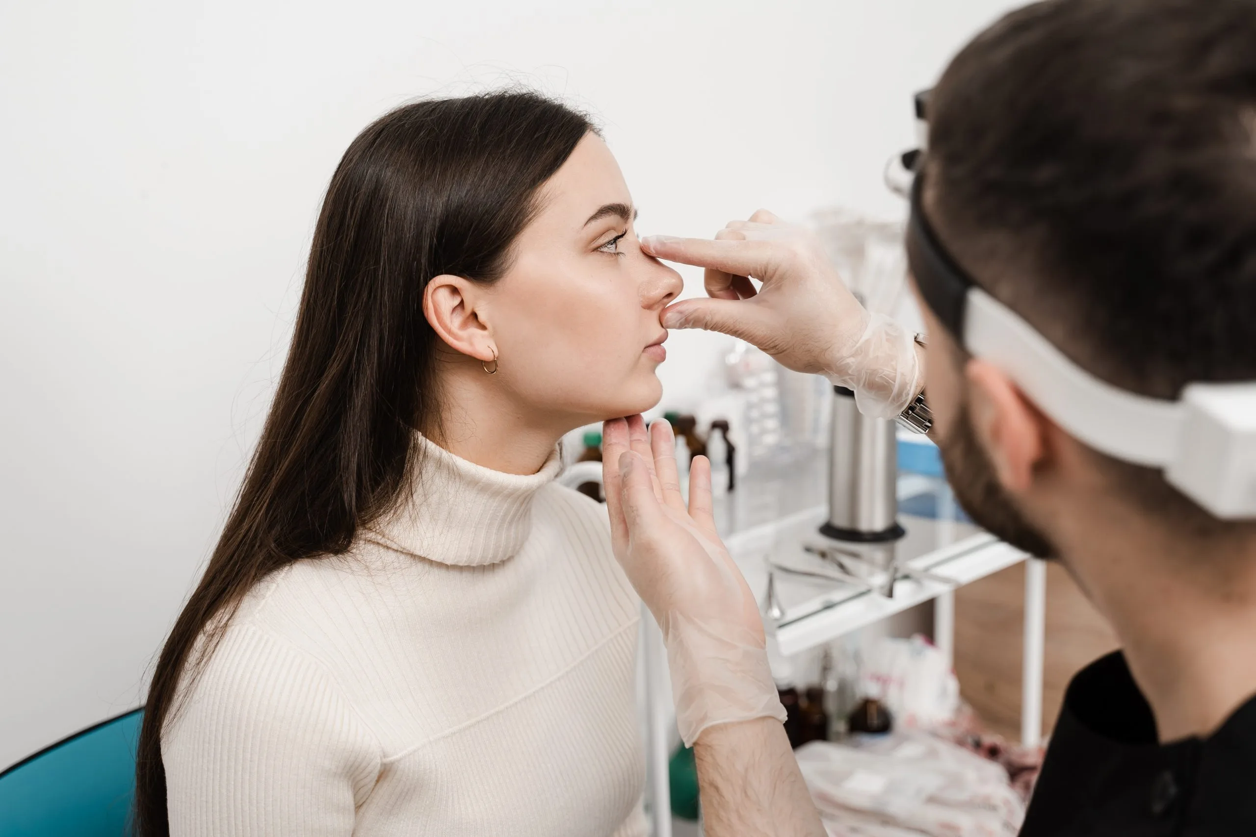 Doctor in gloves examining patient's nose during consultation