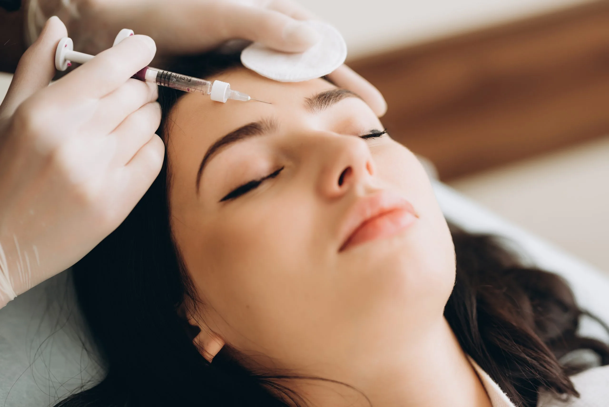Practitioner administering injection into patient's forehead during aesthetic treatment