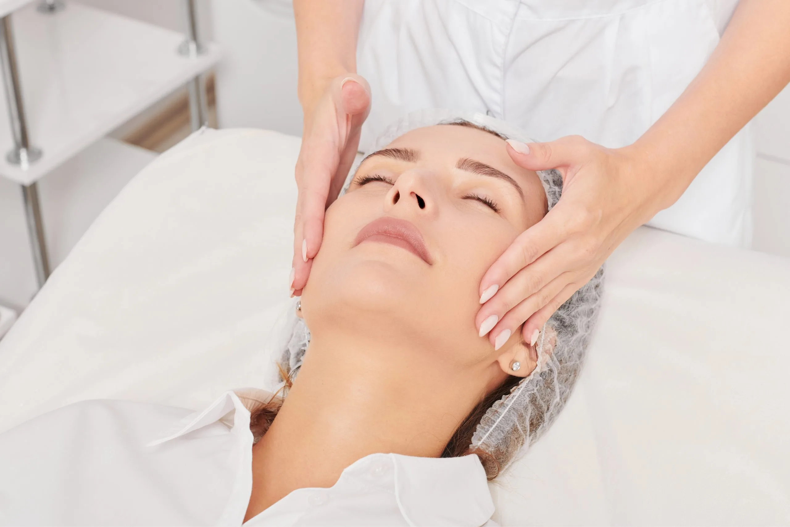 Practitioner's hands performing facial massage or treatment on relaxed patient