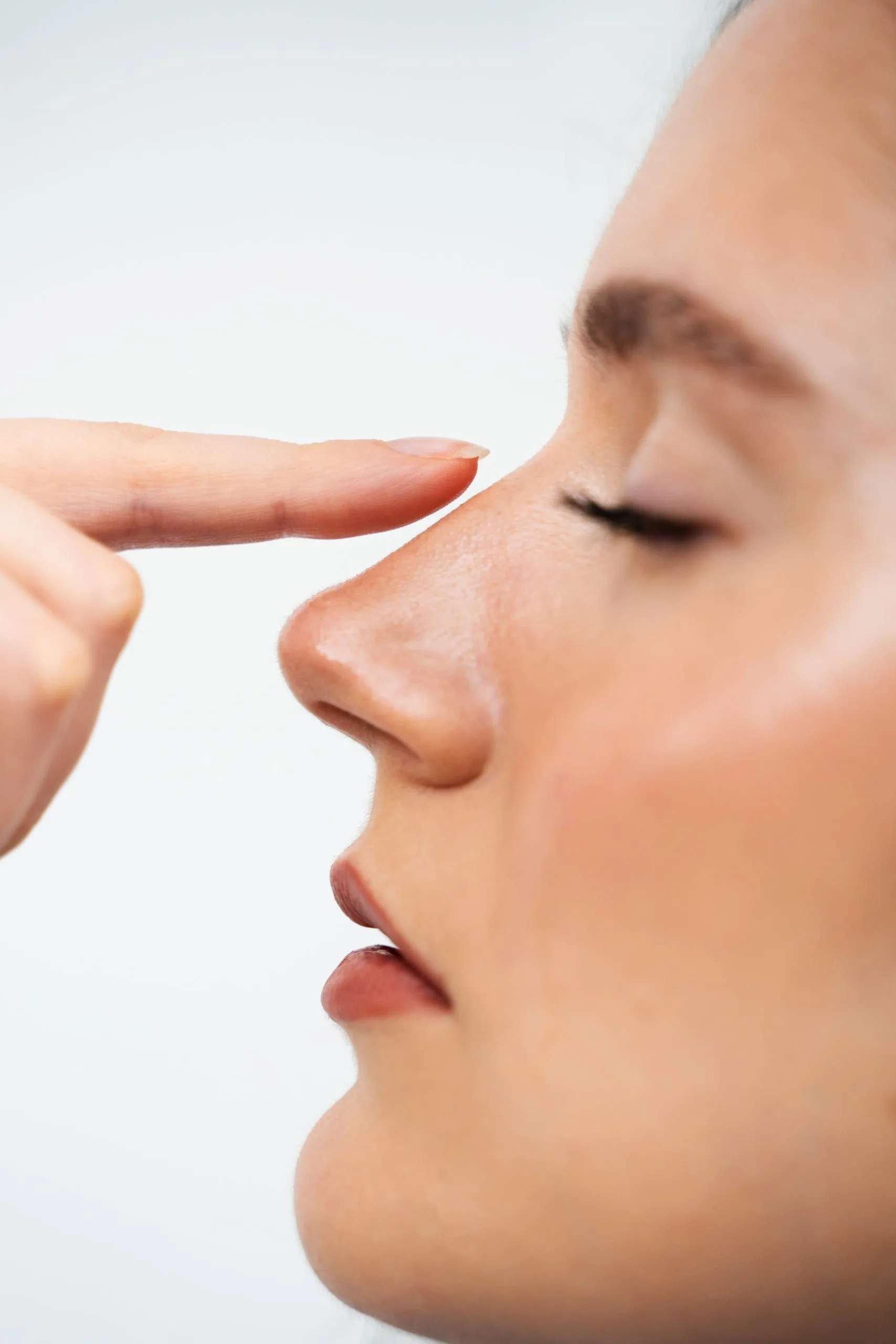 Woman in profile with hand pointing to her nose
