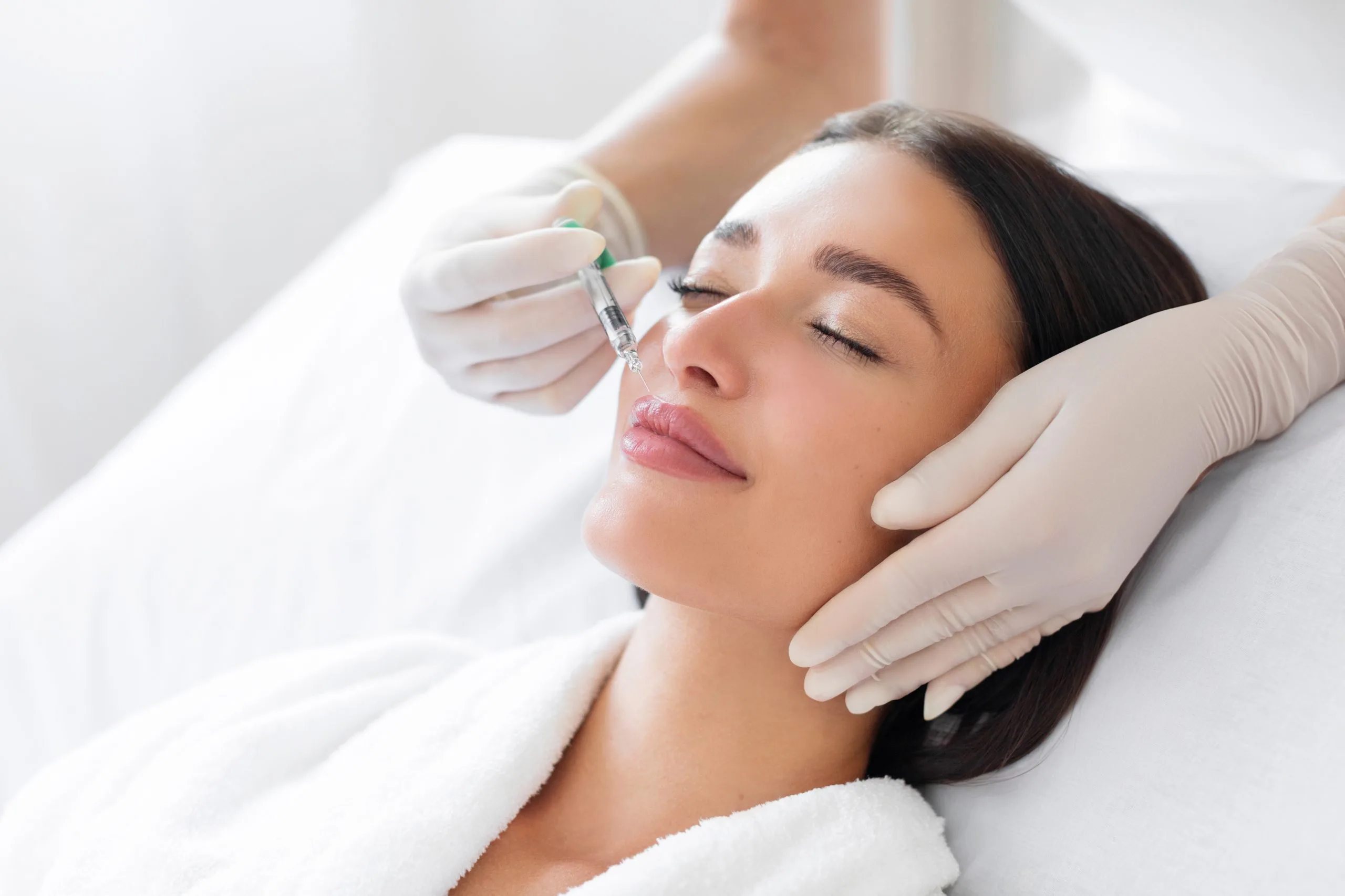 Provider injecting filler into patient's cheek and jawline area