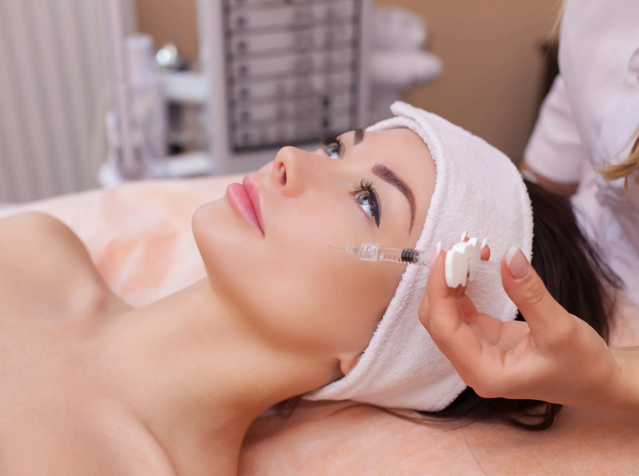Practitioner injecting filler into patient's cheek during aesthetic treatment