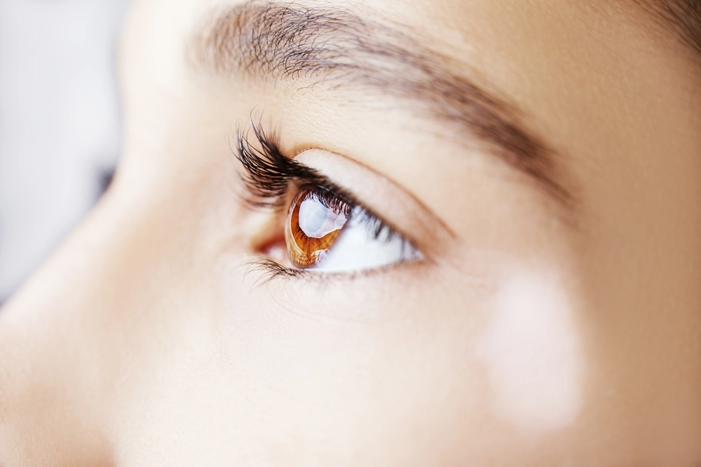 Close-up of a person's eye with amber-brown iris and dark eyelashes