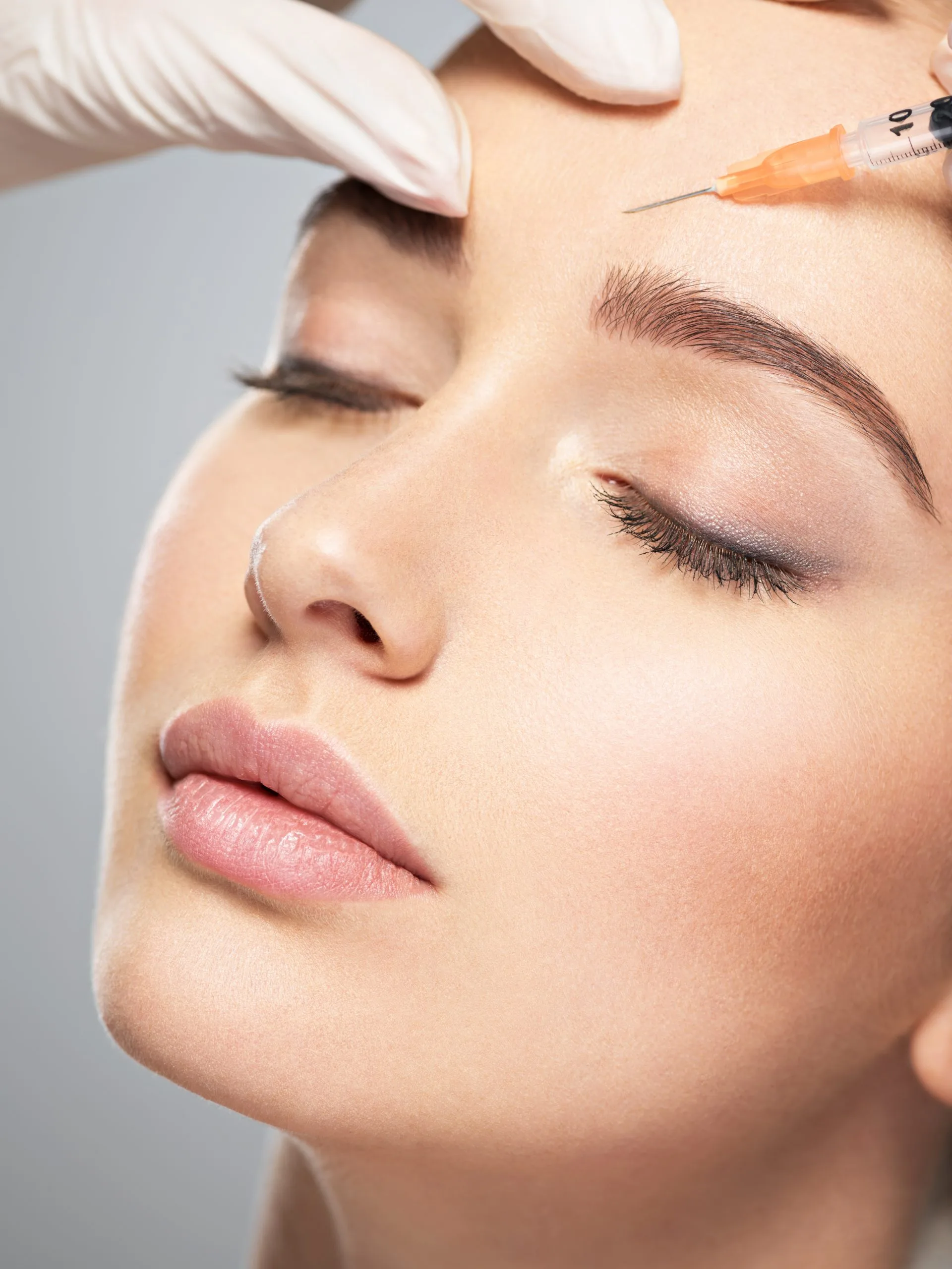 Clinician injecting filler near patient's eye area during cosmetic procedure