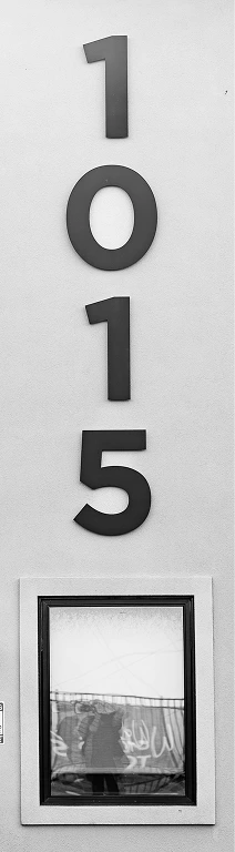 Address numbers 1015 mounted on white wall with window below