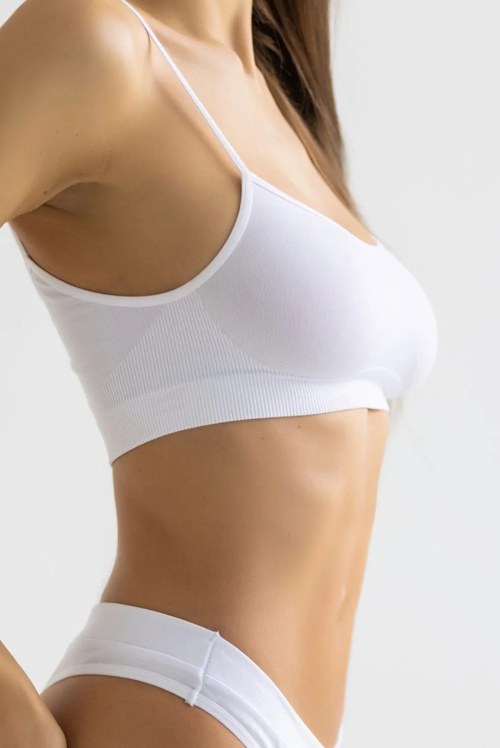 Woman's torso in white sports bra showing defined abdominal and chest area
